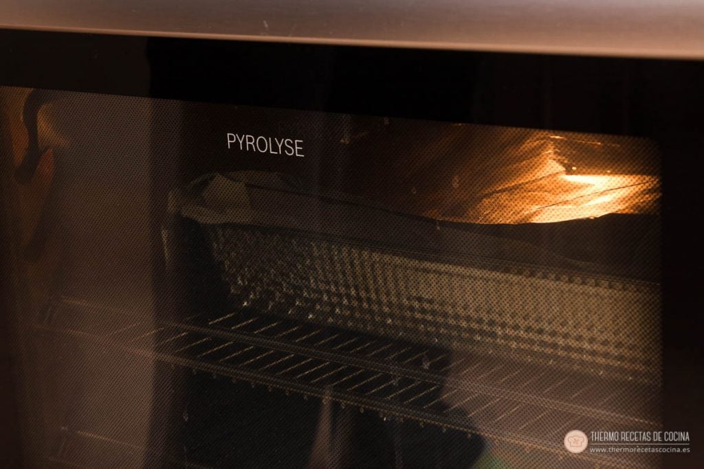 Interior del horno con la coca de llanda horneándose, vista a través del cristal de la puerta