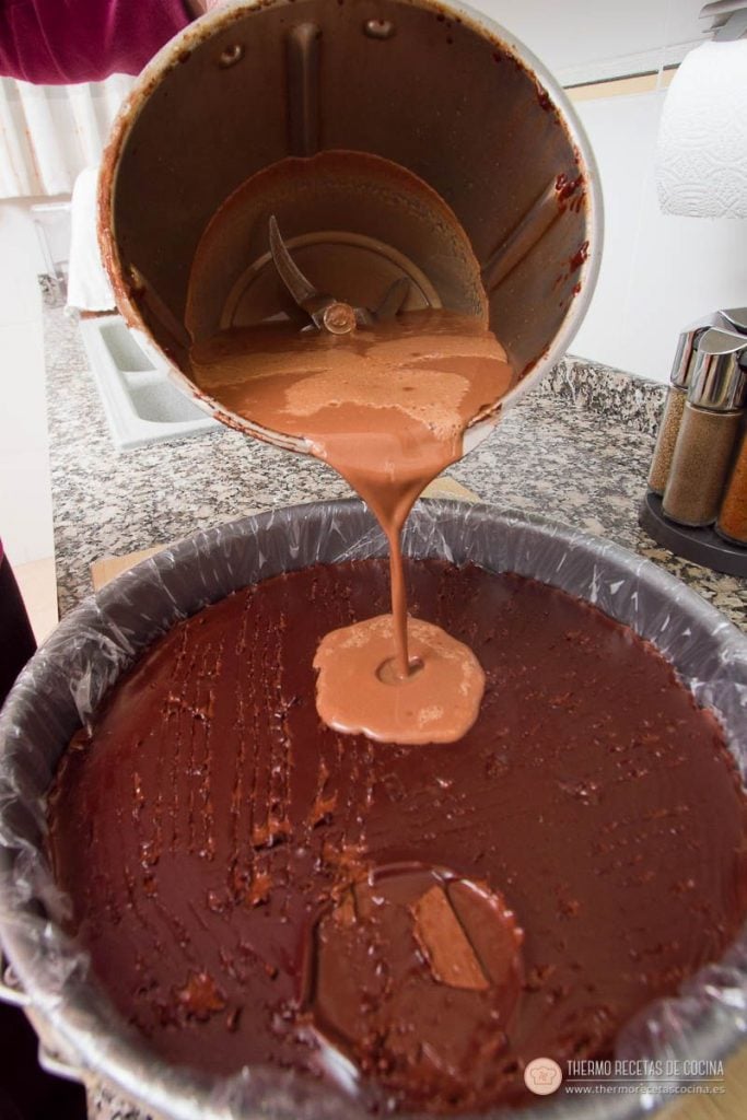 Capa de chocolate con leche vertiéndose sobre la de chocolate negro ya cuajada, con las marcas del tenedor bien visibles en la superficie