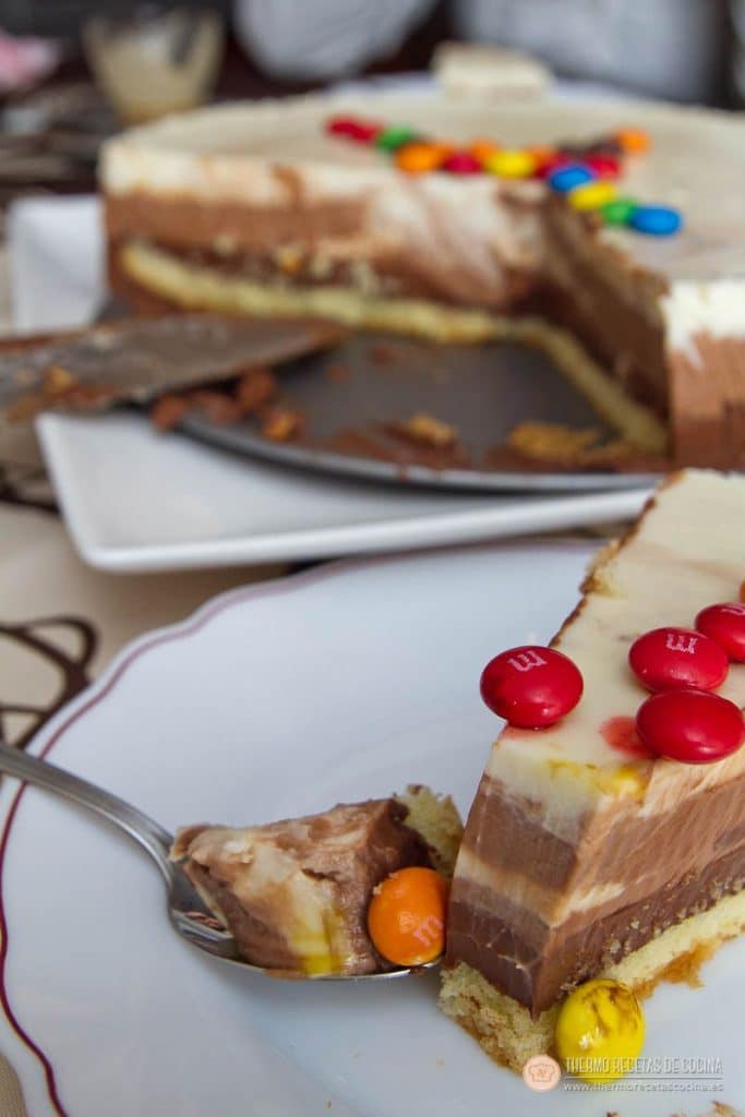 Porción de tarta servida en un plato, con las tres capas de chocolate bien marcadas sobre la base de bizcocho