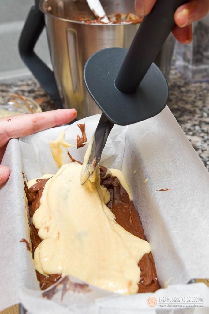 Plum-cake veteado | 14 | Thermo Recetas Cocina Espátula extendiendo una capa de masa clara sobre la de chocolate dentro del molde, dejando las dos a la vista