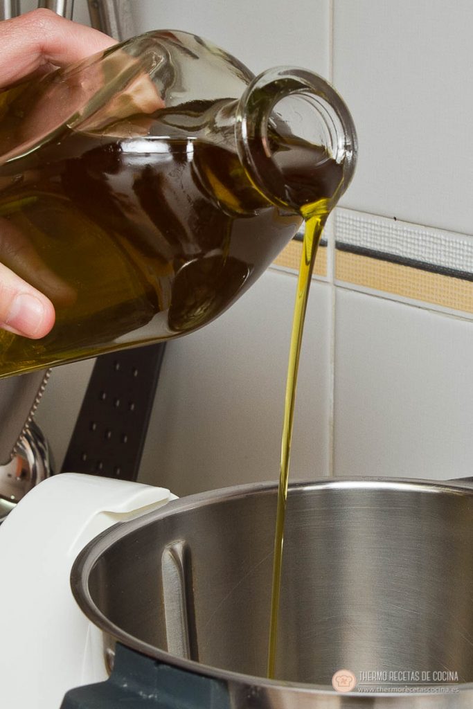 aceite de oliva cayendo desde una botella de cristal dentro del vaso vacío de la Thermomix