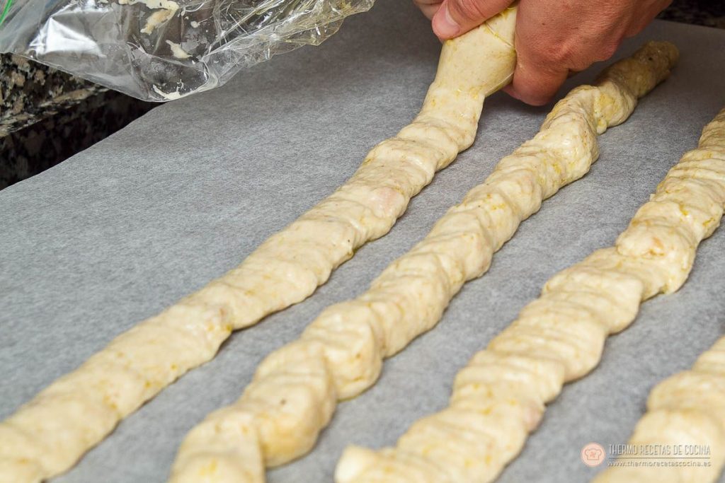 cordones de masa de croqueta ya fría sobre papel de horno, cortándolos a mano en porciones