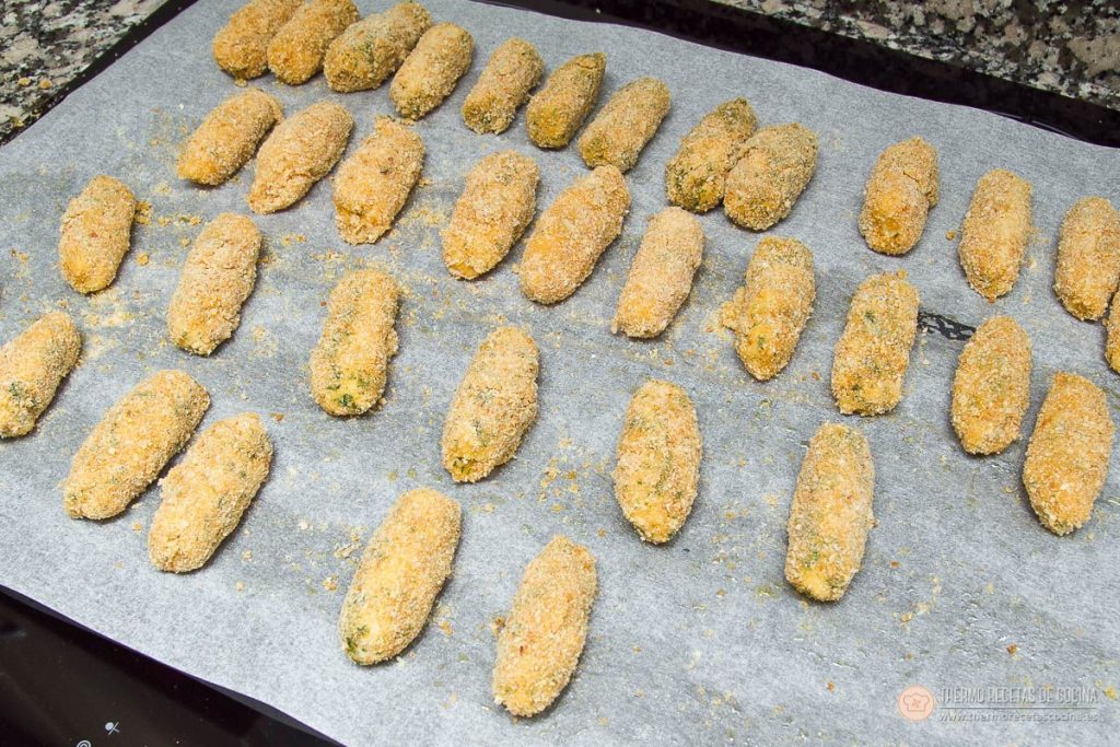 la bandeja completa de croquetas de atún empanadas sobre papel de horno, antes de freír o congelar