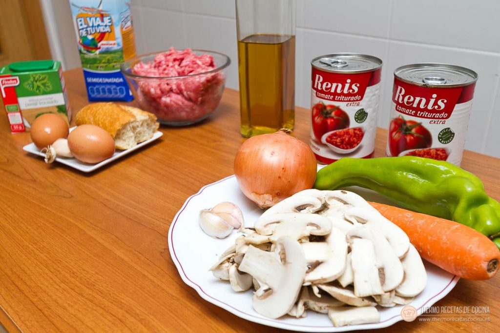 Albóndigas en salsa de tomate en Varoma | 3 | Recetas de cocina para Thermomix Los ingredientes sobre la mesa: carne picada, pan, huevos, leche, ajos, dos latas de tomate triturado, cebolla, pimientos verdes, zanahoria y champiñones laminados