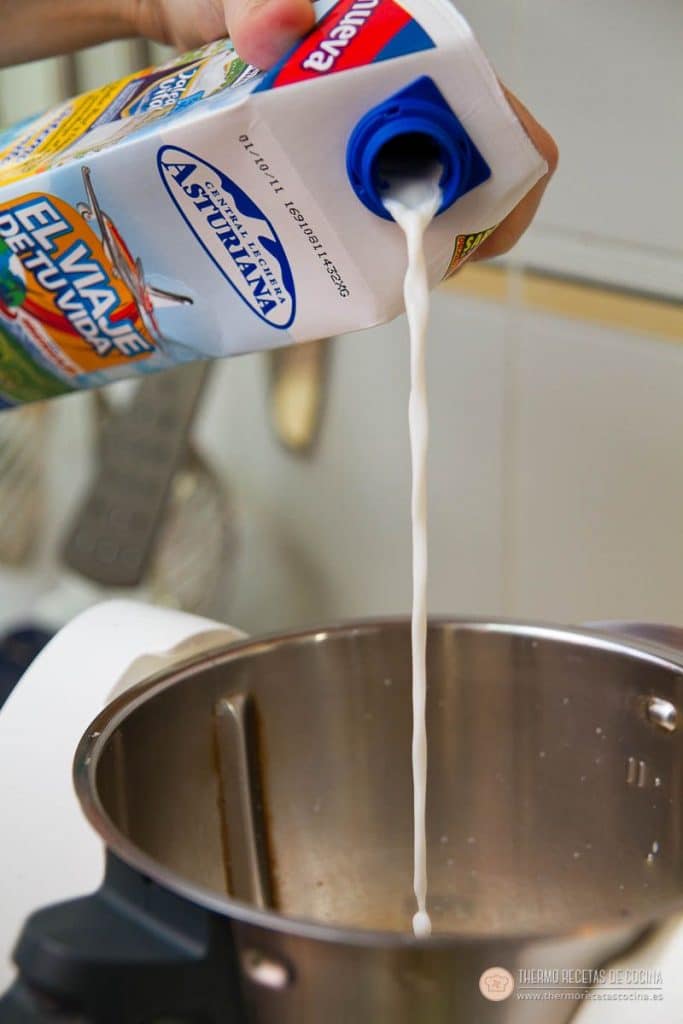 Vertiendo la leche desde el brik dentro del vaso de la Thermomix, que ya tiene los huevos