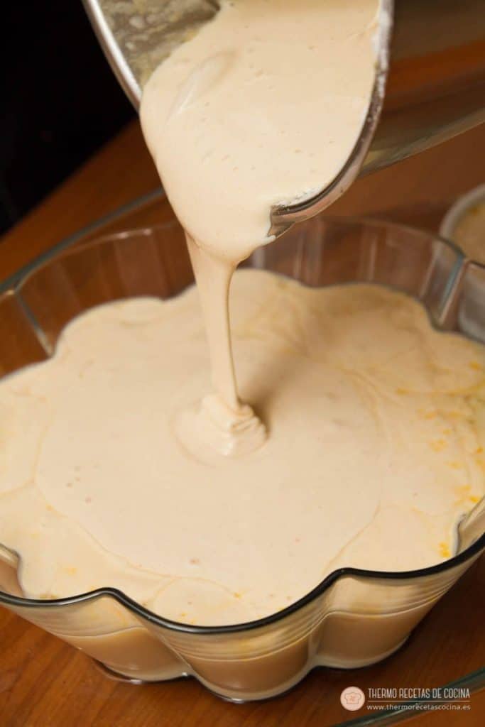 Masa de bizcocho, más espesa y clara, cayendo sobre el flan ya vertido en el molde acanalado
