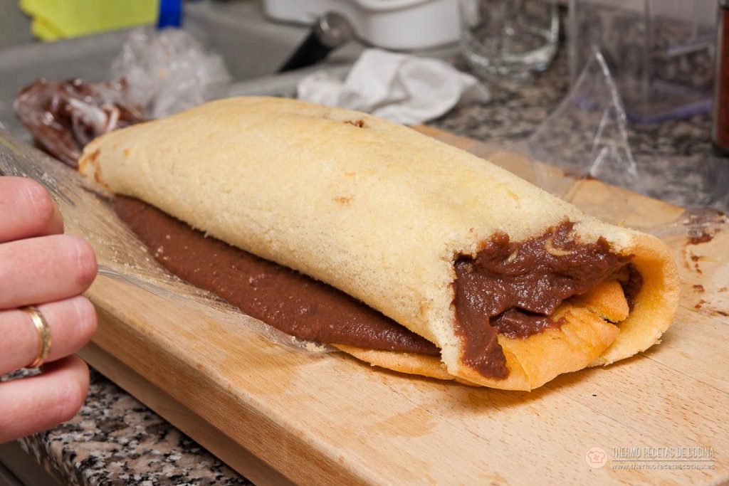el tronco a medio enrollar, con la trufa de chocolate asomando por el corte del bizcocho