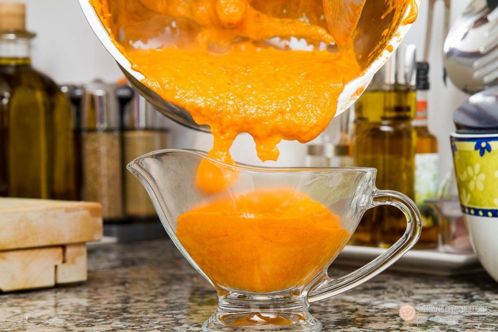 Salsa brava en thermomix | 4 | Thermo Recetas Cocina salsa brava recién triturada, fina y anaranjada, cayendo del vaso a una salsera de cristal