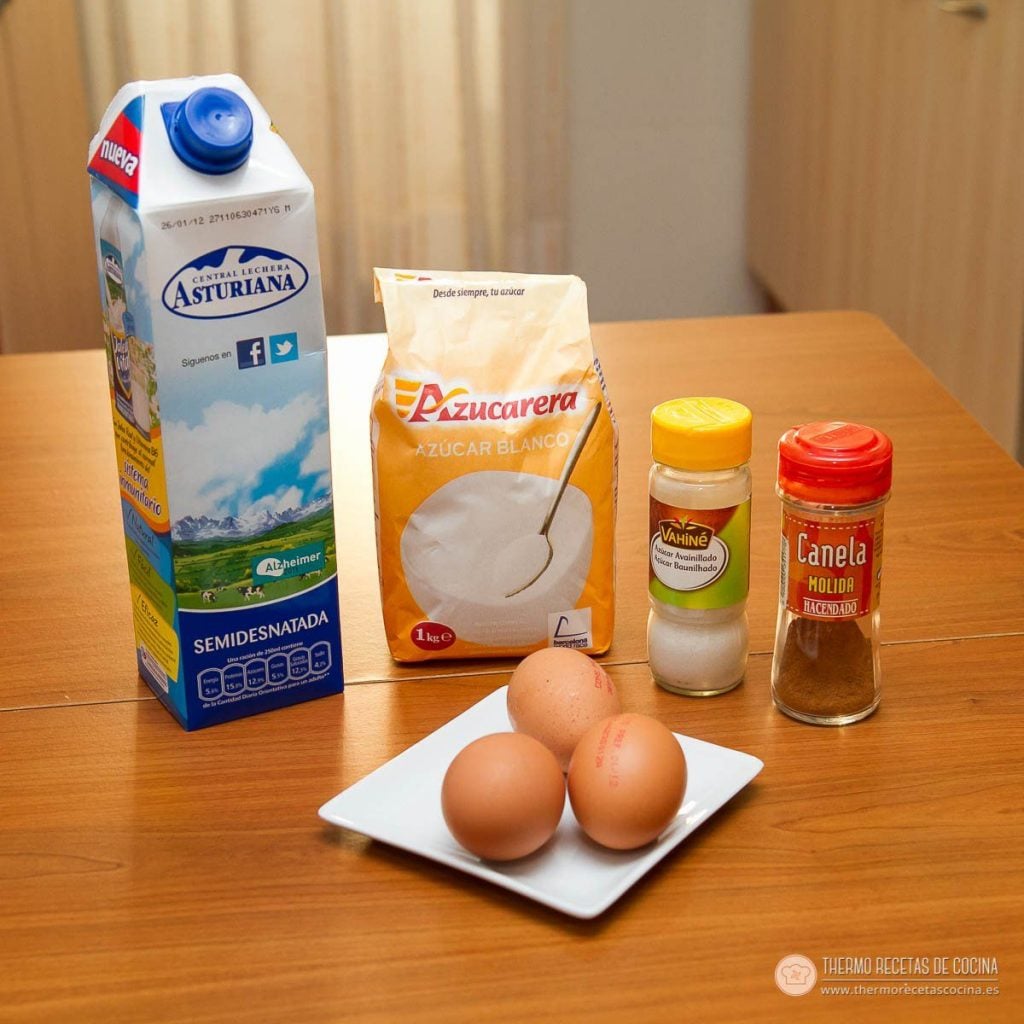 Natillas | 3 | Recetas de cocina para Thermomix Brik de leche semidesnatada, paquete de azúcar blanco, botecito de azúcar avainillado, bote de canela molida y tres huevos en un plato blanco sobre la mesa