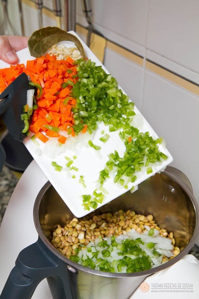 Verduras troceadas —zanahoria, pimiento verde, cebolla y ajo— vertidas sobre las lentejas dentro del vaso de la Thermomix