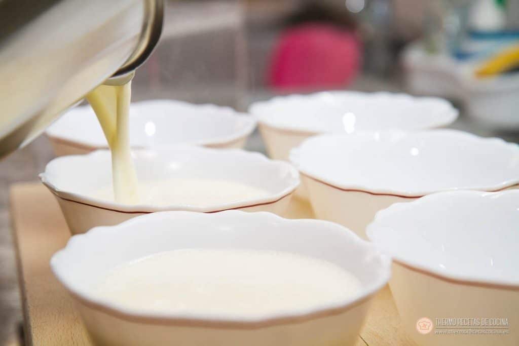 Natillas | 8 | Recetas de cocina para Thermomix Vertiendo la crema de las natillas desde el vaso de la Thermomix a una fila de cuencos blancos