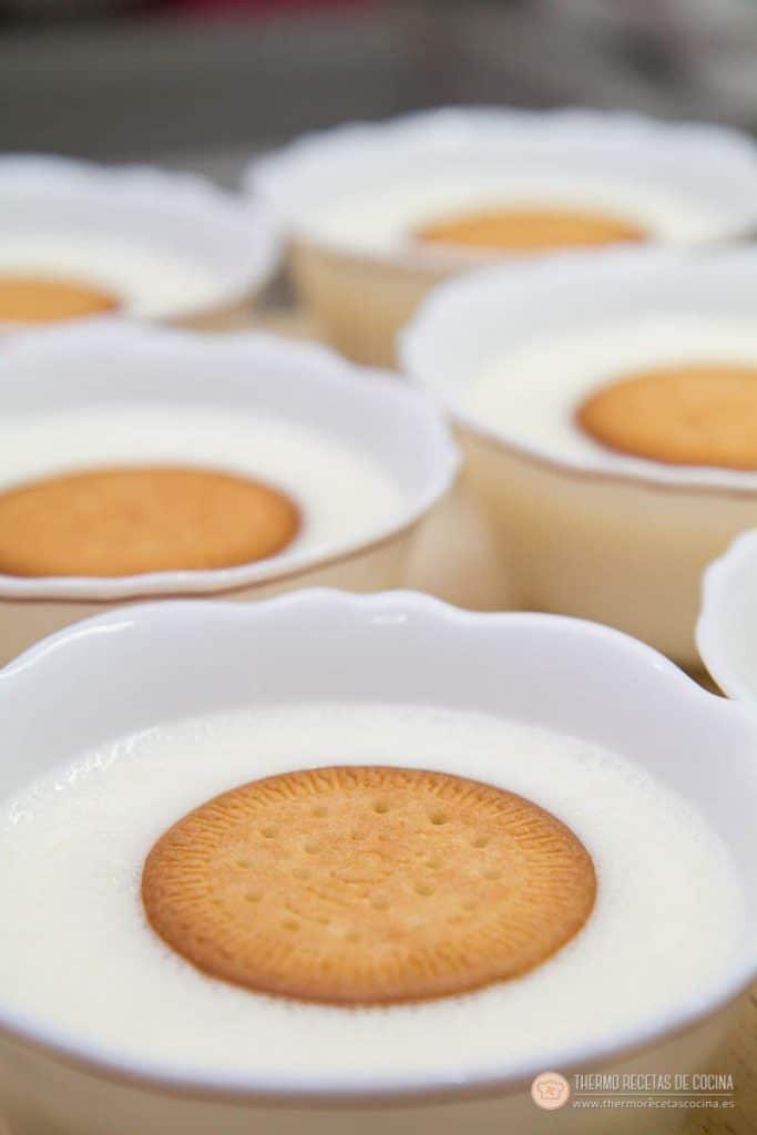 Natillas | 9 | Recetas de cocina para Thermomix Cuenco de natillas recién llenado, con una galleta María apoyada en el centro sobre la crema todavía líquida