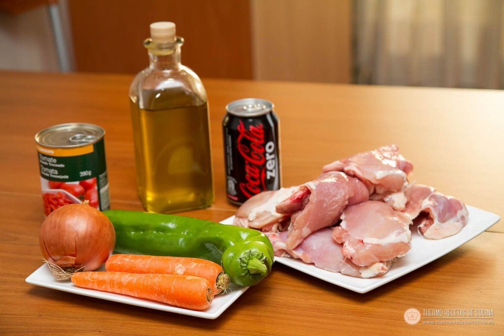 Los ingredientes sobre la mesa: pollo sin piel, cebolla, pimiento verde, zanahorias, lata de tomate triturado, aceite y la lata de Coca-Cola Zero que tenía en casa