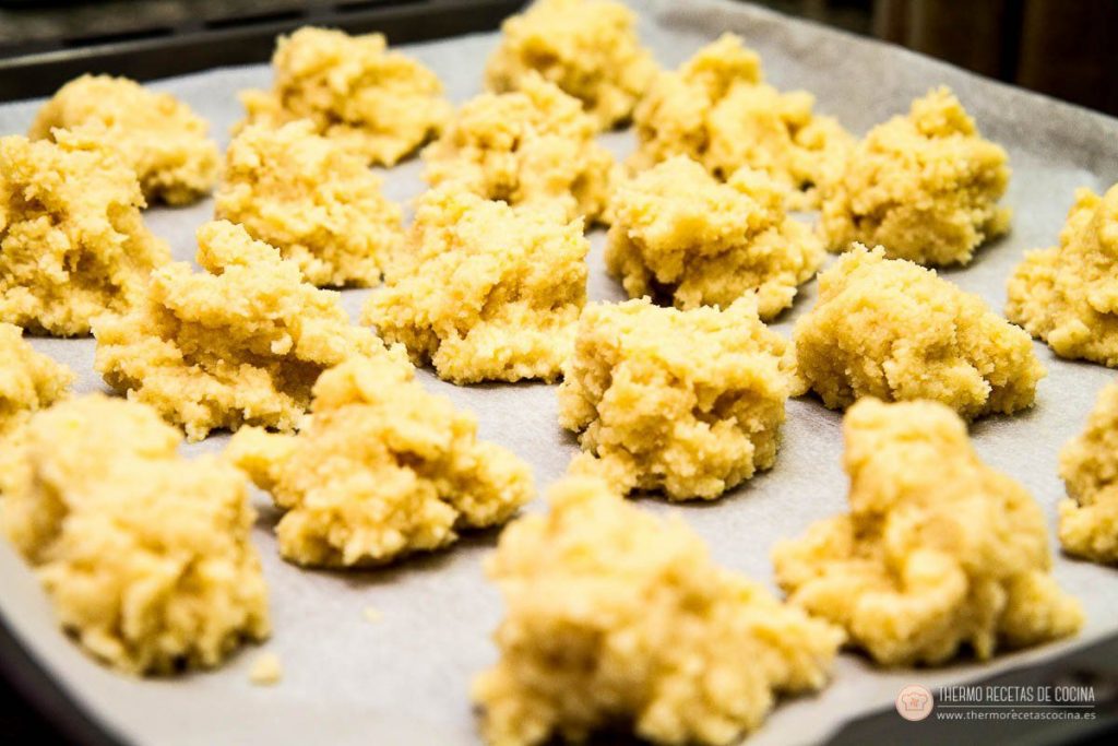 montoncitos de masa de almendrados formados a mano sobre la bandeja de horno, listos para meter al horno