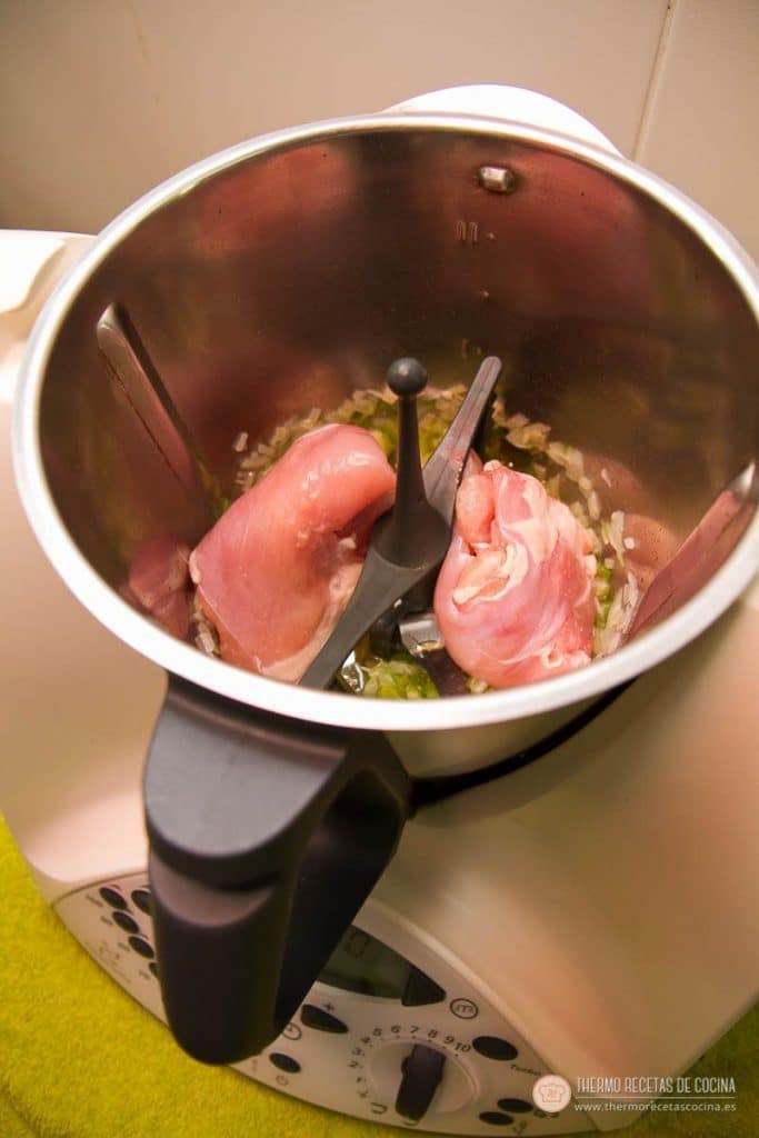 Muslos de pollo colocados sobre el sofrito, con la mariposa puesta en las cuchillas del vaso