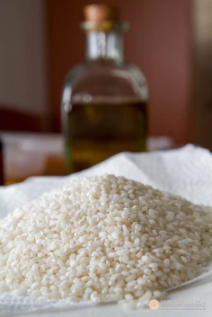 Arroz con pollo y chorizo | 3 | Recetas de cocina para Thermomix Montón de arroz redondo crudo sobre un paño blanco, con la aceitera de cristal detrás