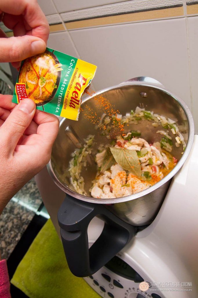 Arroz con pollo y chorizo | 10 | Recetas de cocina para Thermomix Sobre de paellero espolvoreándose sobre el sofrito de pollo, chorizo y verdura, con la hoja de laurel visible en el vaso