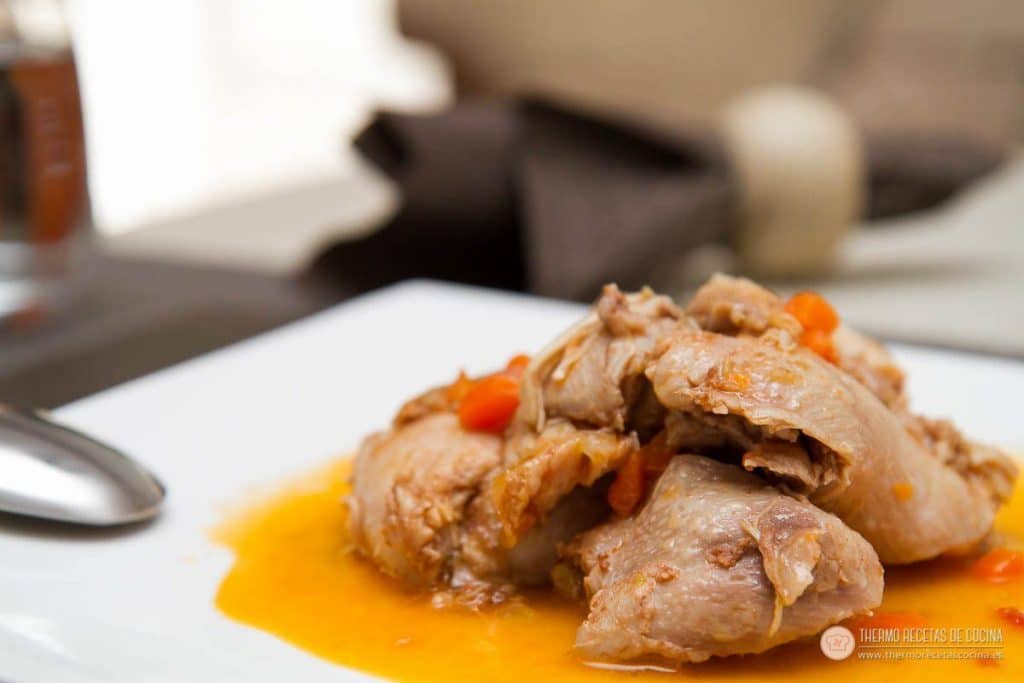 Primer plano del pollo a la coca-cola terminado, deshaciéndose del hueso, con dados de zanahoria y la salsa por debajo