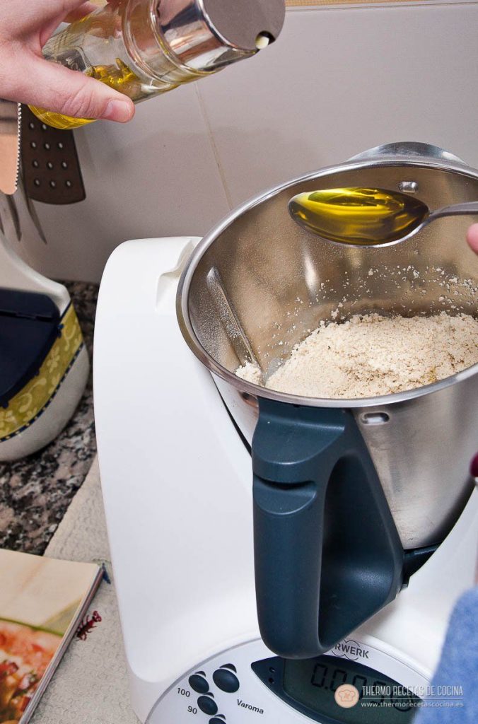 Cucharada de aceite de oliva añadiéndose sobre la harina dentro del vaso