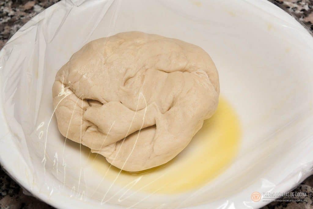 La bola de masa colocada en el bol engrasado y tapada con film, antes de las dos horas de reposo