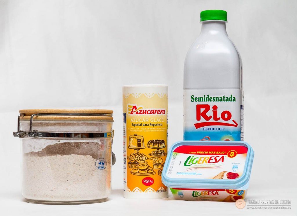 ingredientes de las pastas de té sobre fondo blanco: un bote de cristal con harina, un envase de azúcar glacé, una botella de leche semidesnatada y una tarrina de margarina ligera
