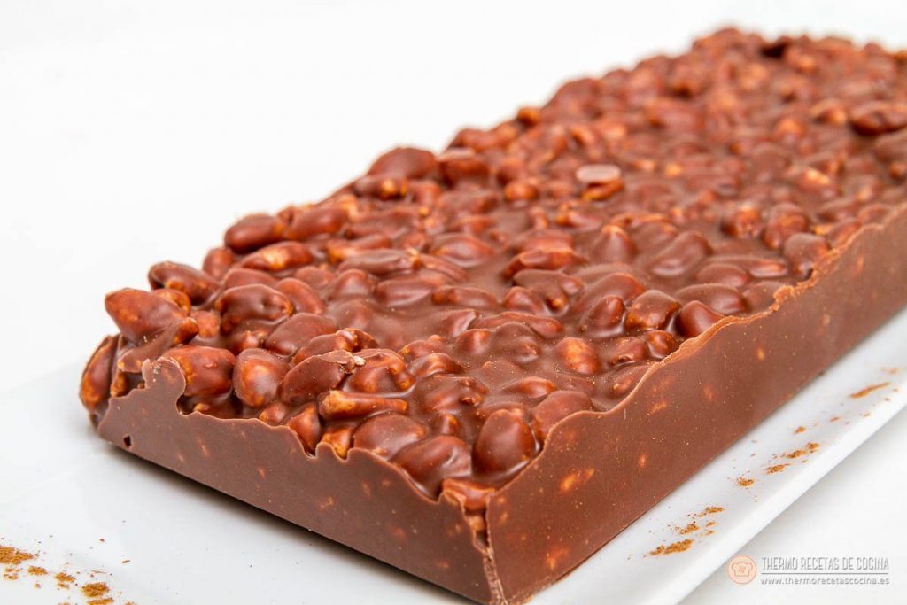 Turrón de chocolate | 6 | Recetas de cocina para Thermomix tableta de turrón de chocolate ya desmoldada sobre un plato blanco, con la superficie rugosa de arroz inflado