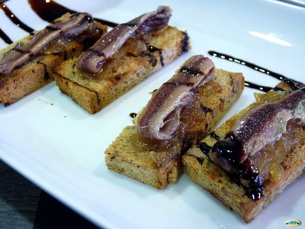 Tostas con anchoas del Cantábrico sobre cebolla confitada y reducción de vinagre balsámico