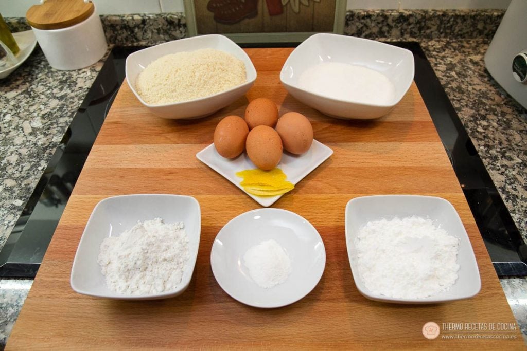 Marquesas | 3 | Thermo Recetas Cocina ingredientes de las marquesas colocados en cuencos sobre una tabla: almendra molida, azúcar, cuatro huevos, tiras de piel de limón, harina, maicena y levadura