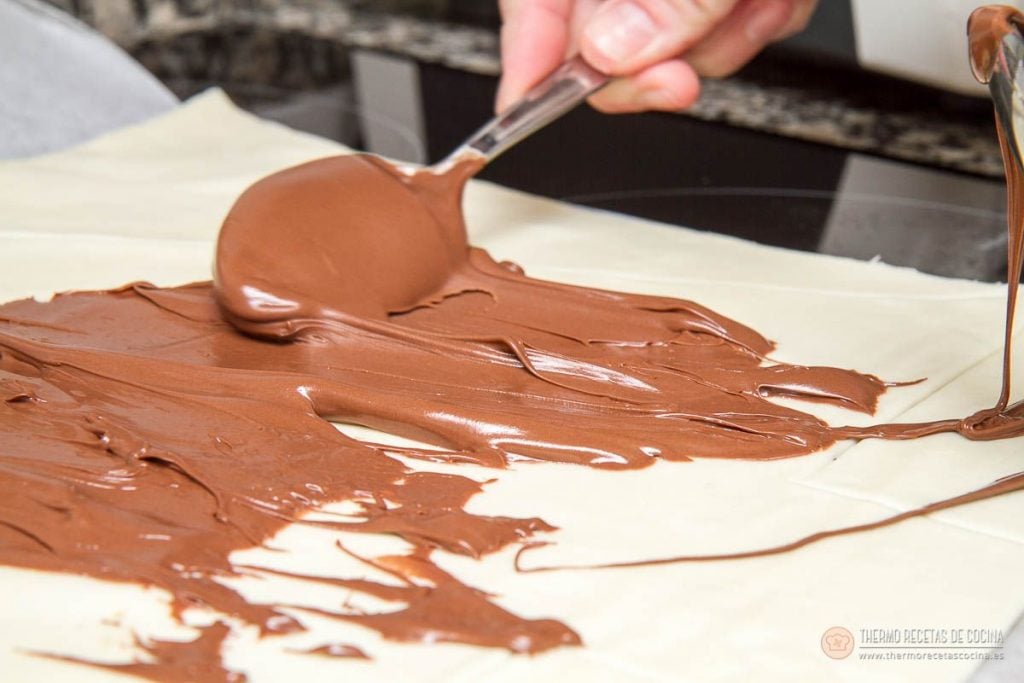 Árbol de Navidad de Nutella y hojaldre | 4 | Thermo Recetas Cocina nutella extendiéndose con una cuchara sobre la plancha de hojaldre hasta casi los bordes