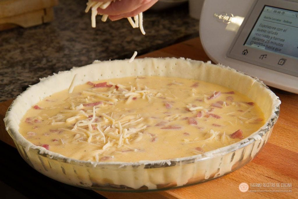 Receta de tarta Quiché de Bacon y Queso | 7 | Recetas de cocina para Thermomix queso rallado cayendo sobre el relleno de la quiche justo antes de meterla al horno