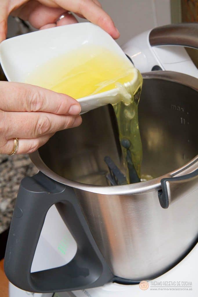 Claras de huevo vertiéndose en el vaso limpio de la Thermomix, con la mariposa ya puesta