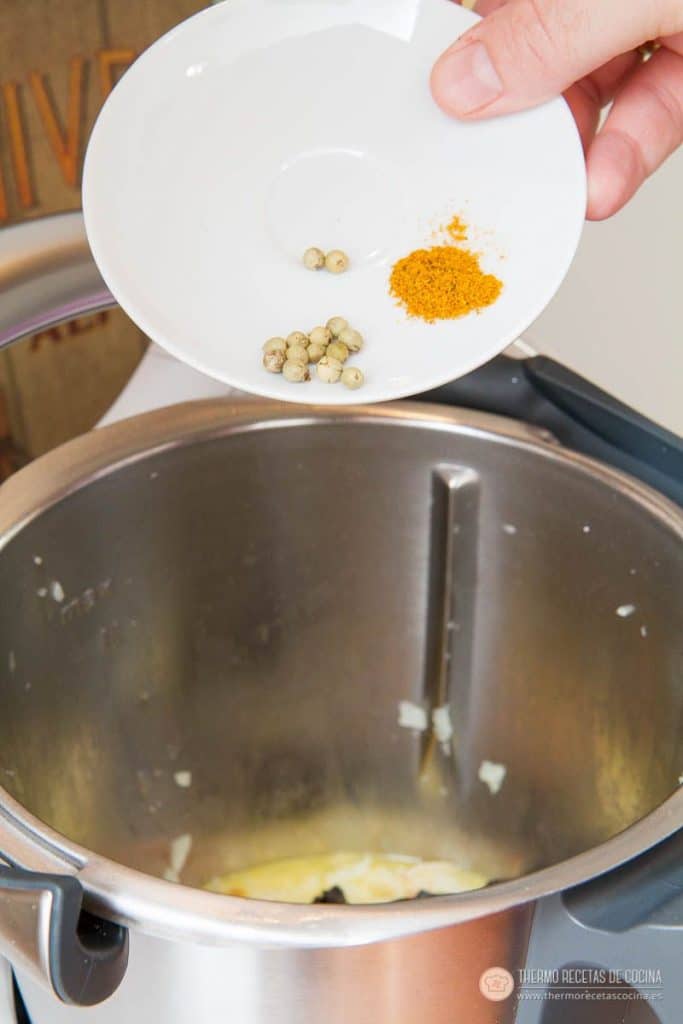 Curry en polvo y bolitas de pimienta verde en conserva sobre un platito, listos para añadir al vaso