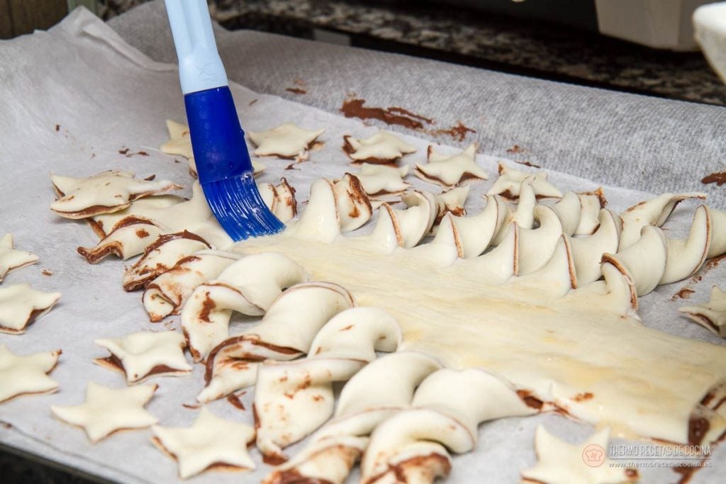Árbol de Navidad de Nutella y hojaldre | 11 | Thermo Recetas Cocina pincelando con huevo batido las ramas ya retorcidas del árbol y las estrellas de alrededor