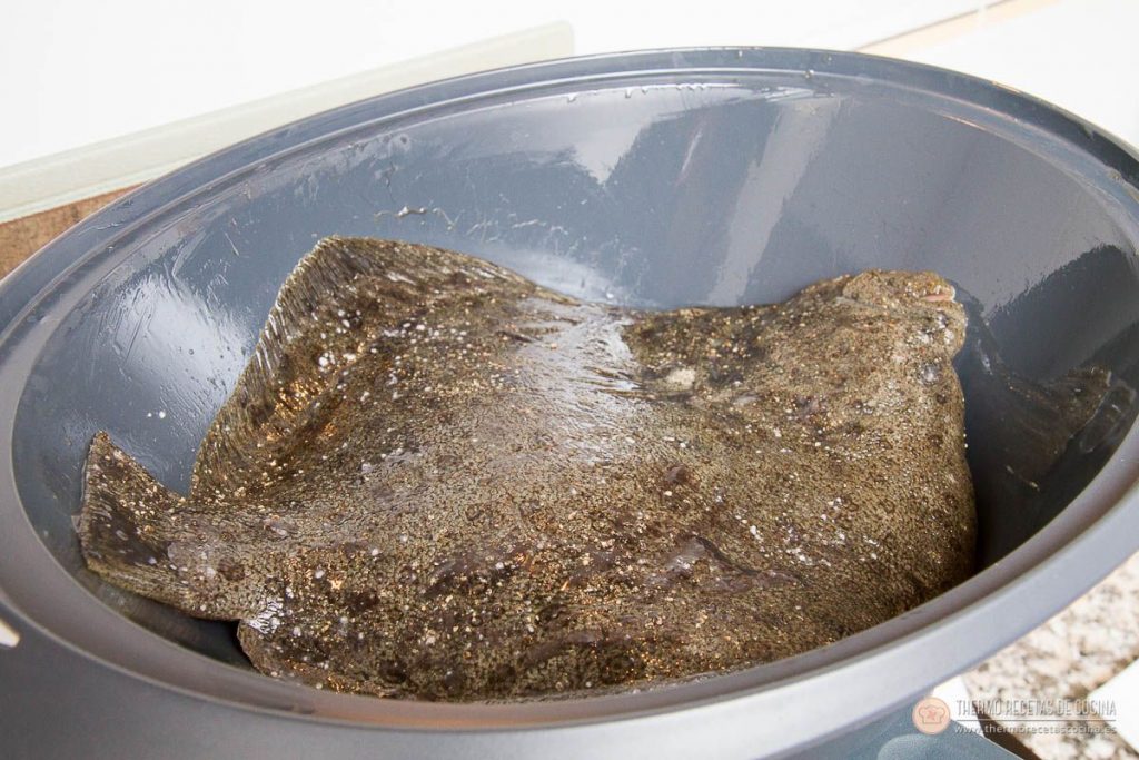 Rodaballo entero y crudo, con la piel oscura hacia arriba, colocado dentro del recipiente Varoma engrasado