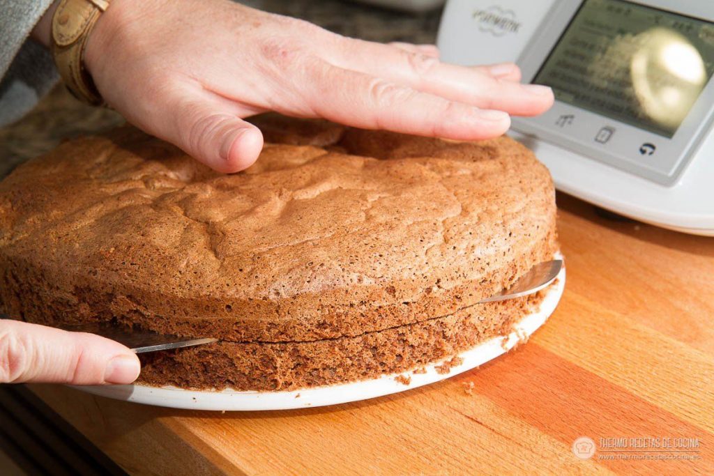 Bizcocho de chocolate ya frío, abriéndose por la mitad en horizontal con un cuchillo