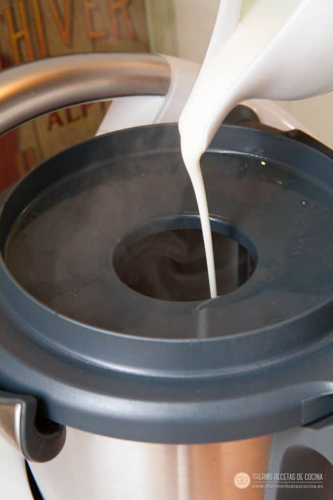 Nata vertiéndose por el orificio de la tapa dentro del vaso con la salsa ya cocinada