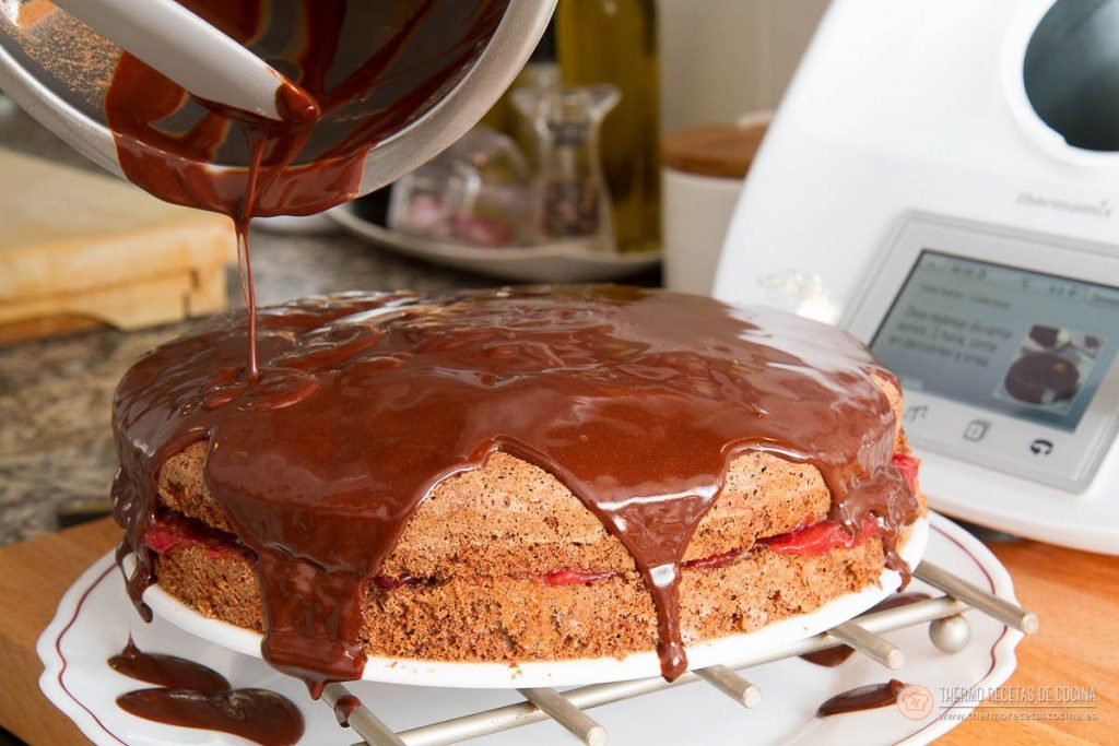 Cobertura de chocolate cayendo sobre la tarta rellena y resbalando por los laterales hasta el plato