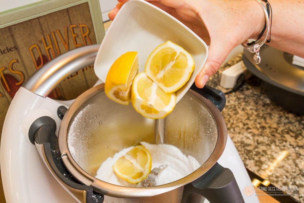 echando las mitades de limón desde un cuenco al vaso, sobre el azúcar ya pulverizado