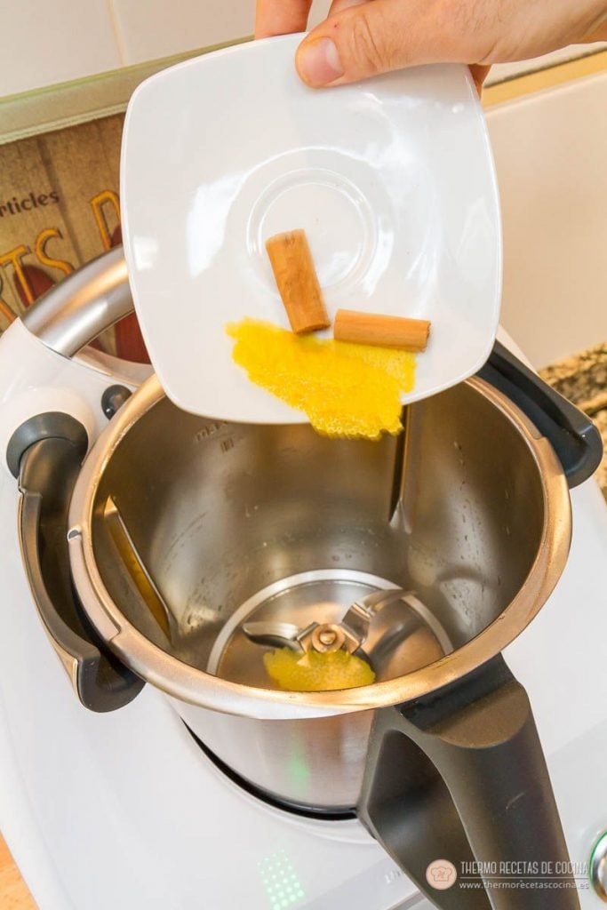 ¿Tardes de calor? Prepara una Leche Merengada con tu Thermomix. | 4 | Recetas de cocina para Thermomix echando la piel de limón y dos ramas de canela desde un platito al vaso de la Thermomix