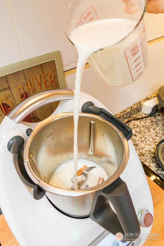 ¿Tardes de calor? Prepara una Leche Merengada con tu Thermomix. | 6 | Recetas de cocina para Thermomix la leche cayendo desde una jarra medidora al vaso, sobre la canela y la piel de limón